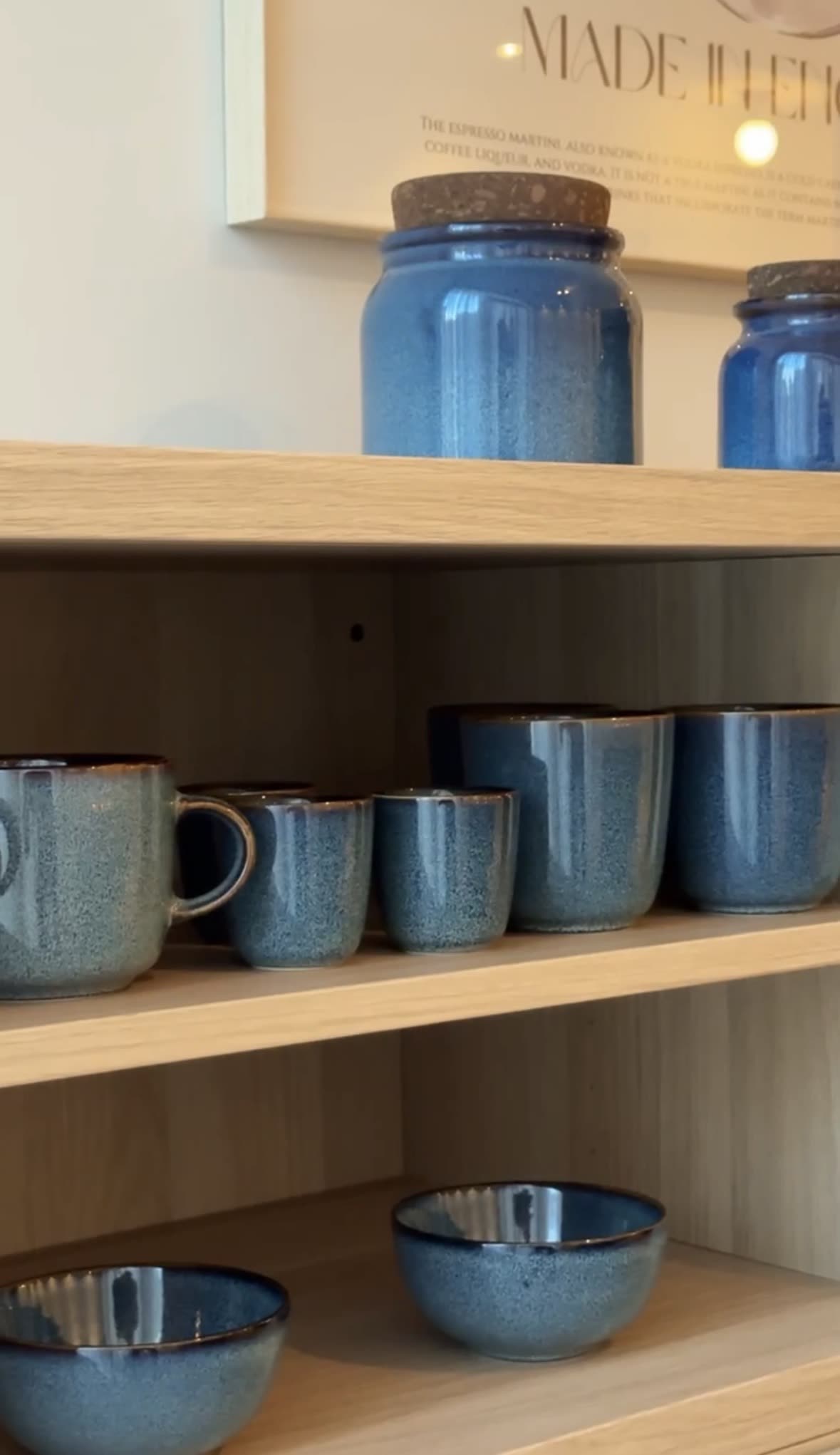Blauwe koffiekopjes, mokken en voorraadpotten in een open kast in de koffiehoek