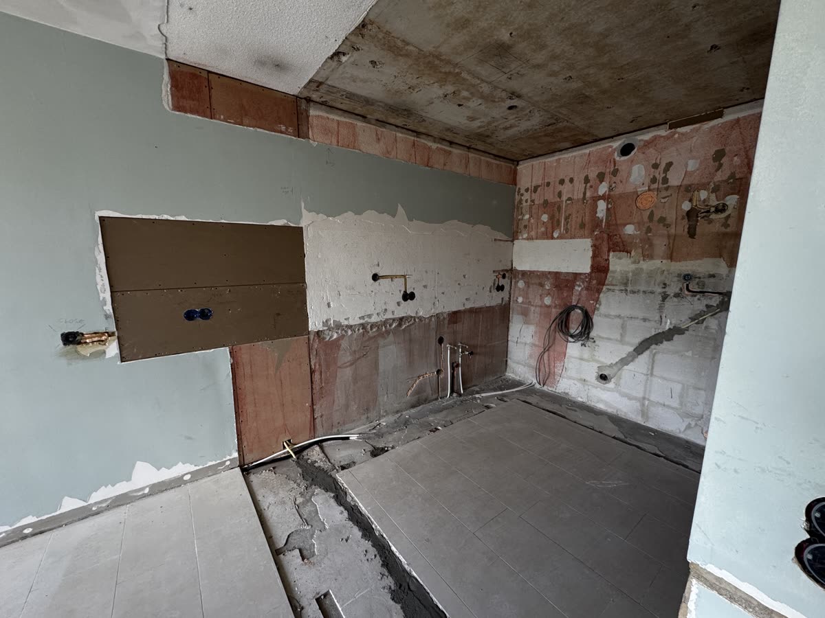 De kale keukenwand met nieuw leidingwerk en elektra, klaar voor de nieuwe keuken